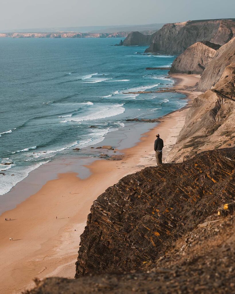 vertical shot of a person on a cliff looking at th 2UR8DY4